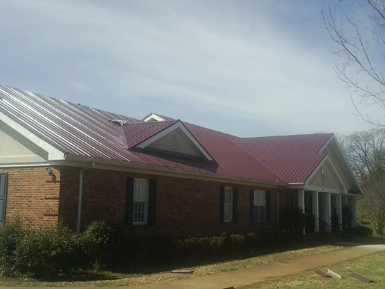 Red metal roof with gabled entries on a long brick building, from a Hail Damage Roof Repair job in Snoqualmie Pass