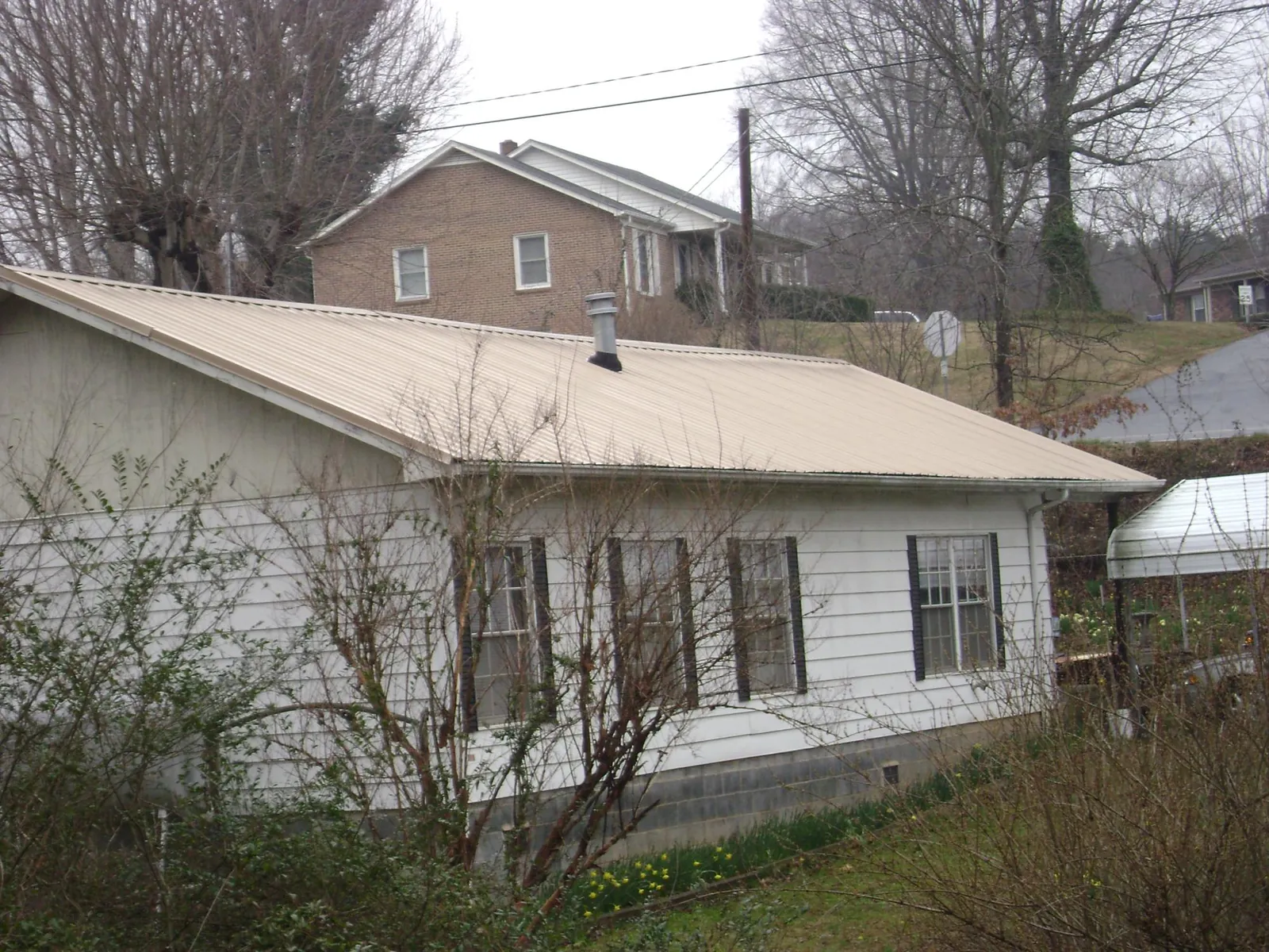 Tan metal roof on a white sided house set into a hillside — Commercial Roofing by Roofing Brothers in Snoqualmie Pass