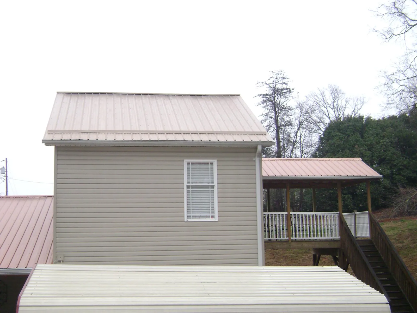 Tan metal roofs on a two story addition and attached porch, from a Roof Replacement job in Snoqualmie Pass