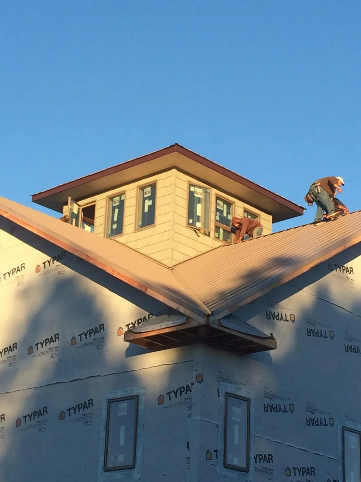 Roofers working around a rooftop cupola on a new metal roof at sunset — Roof Waterproofing in Snoqualmie Pass by Roofing Brothers